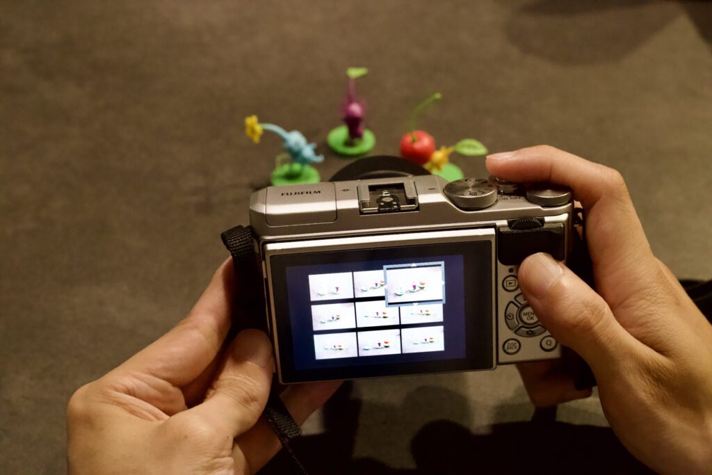机の上でカメラ液晶を指先で確認し、同じ被写体を何度も撮影する様子